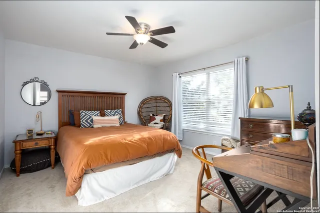 a bedroom with a bed a desk and chair with a window