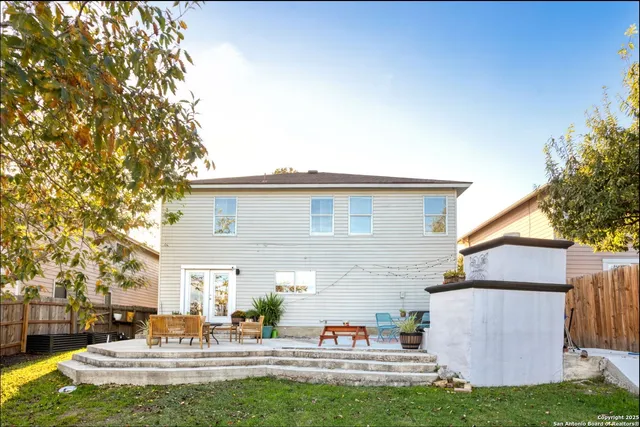 a view of a white house with a fountain and a large tree