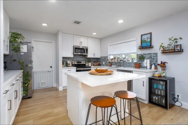 a kitchen with granite countertop a stove top oven a sink dishwasher a dining table and chairs with wooden floor