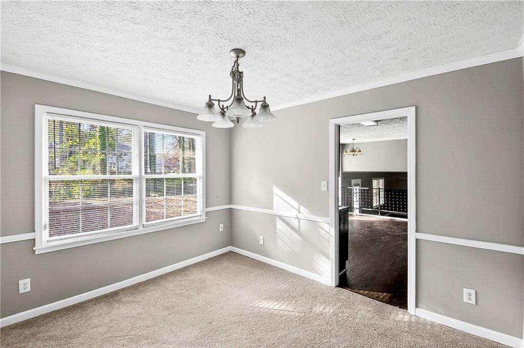 1075 Forest Heights Road Stone Mountain, GA 30083 - Photo 13 of 42 an empty room with chandelier and windows