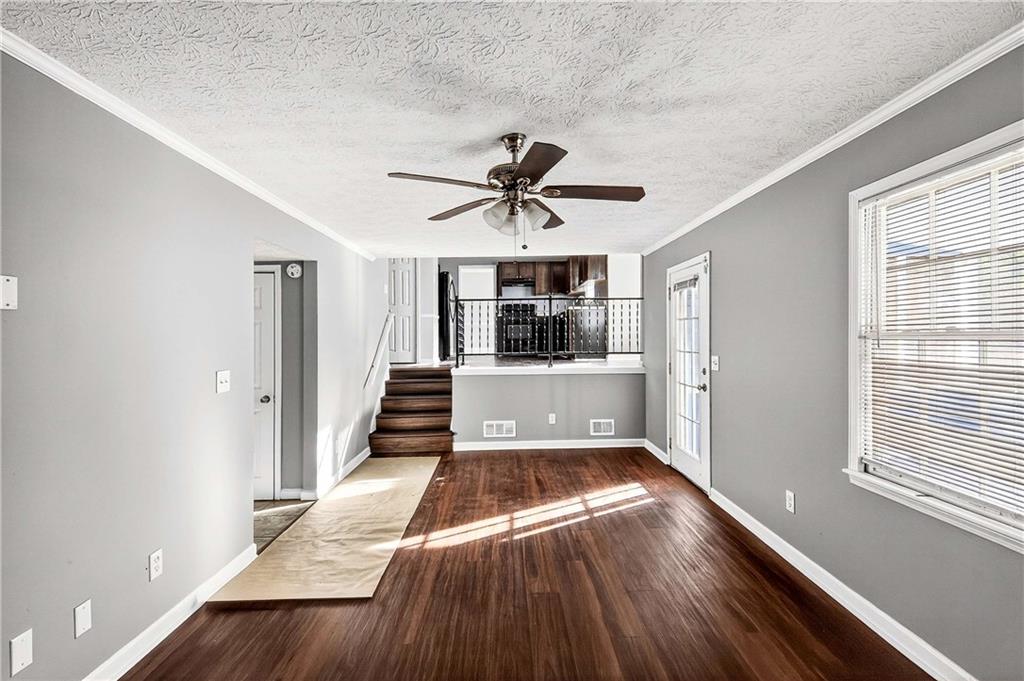 1075 Forest Heights Road Stone Mountain, GA 30083 - Photo 20 of 42 a view of a living room with a kitchen island wooden floor and a ceiling fan