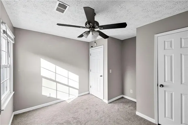 an empty room with windows and fan