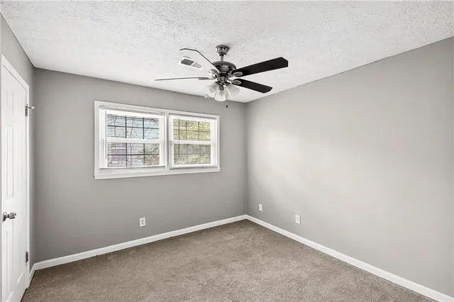 an empty room with a window and a ceiling fan