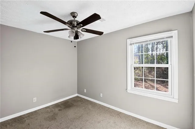 an empty room with window and a ceiling fan