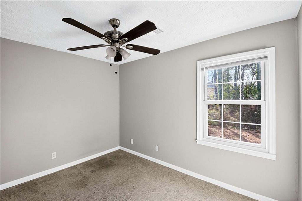 1075 Forest Heights Road Stone Mountain, GA 30083 - Photo 30 of 42 an empty room with window and a ceiling fan