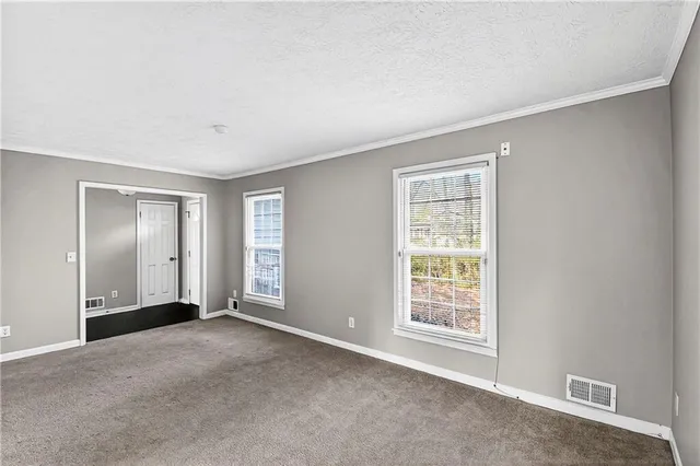a view of an empty room with window and wooden floor