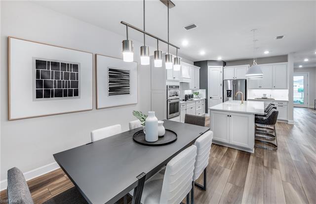 3974 East Hampton Circle Fort Myers, FL 33905 - Photo 15 of 36 a kitchen with stainless steel appliances kitchen island granite countertop a table chairs in it and wooden floors