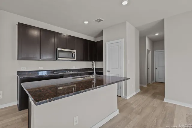 a kitchen with stainless steel appliances granite countertop a sink and a refrigerator