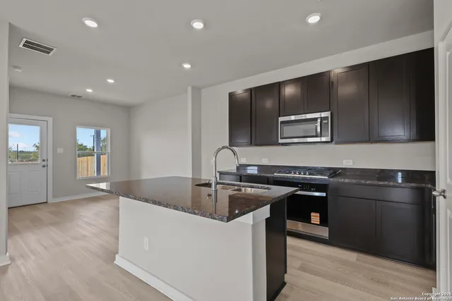 a kitchen with kitchen island granite countertop a sink and refrigerator