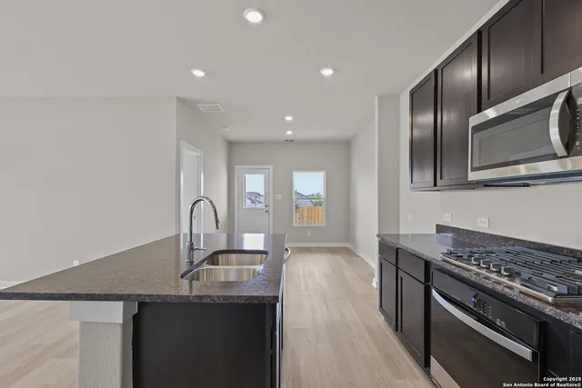 a kitchen with stainless steel appliances granite countertop a sink a stove and cabinets