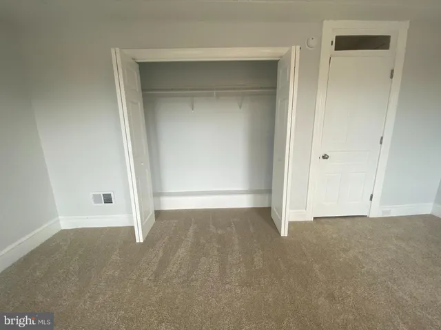 an empty room with ceiling fan and windows