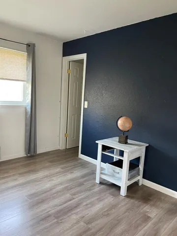 a bedroom with wooden floor and a window