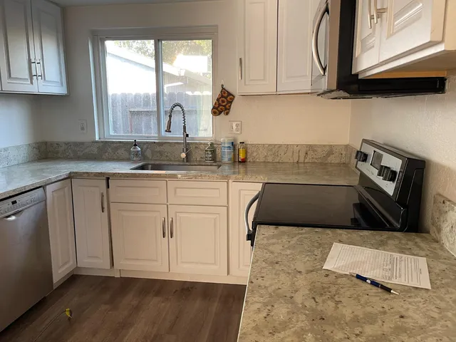 a kitchen with granite countertop a sink a stove and cabinets
