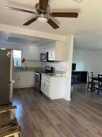 a kitchen with granite countertop a stove cabinets and wooden floor