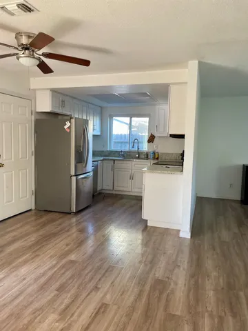 a kitchen with stainless steel appliances a refrigerator a sink dishwasher a stove top oven a dining table and chairs with wooden floor