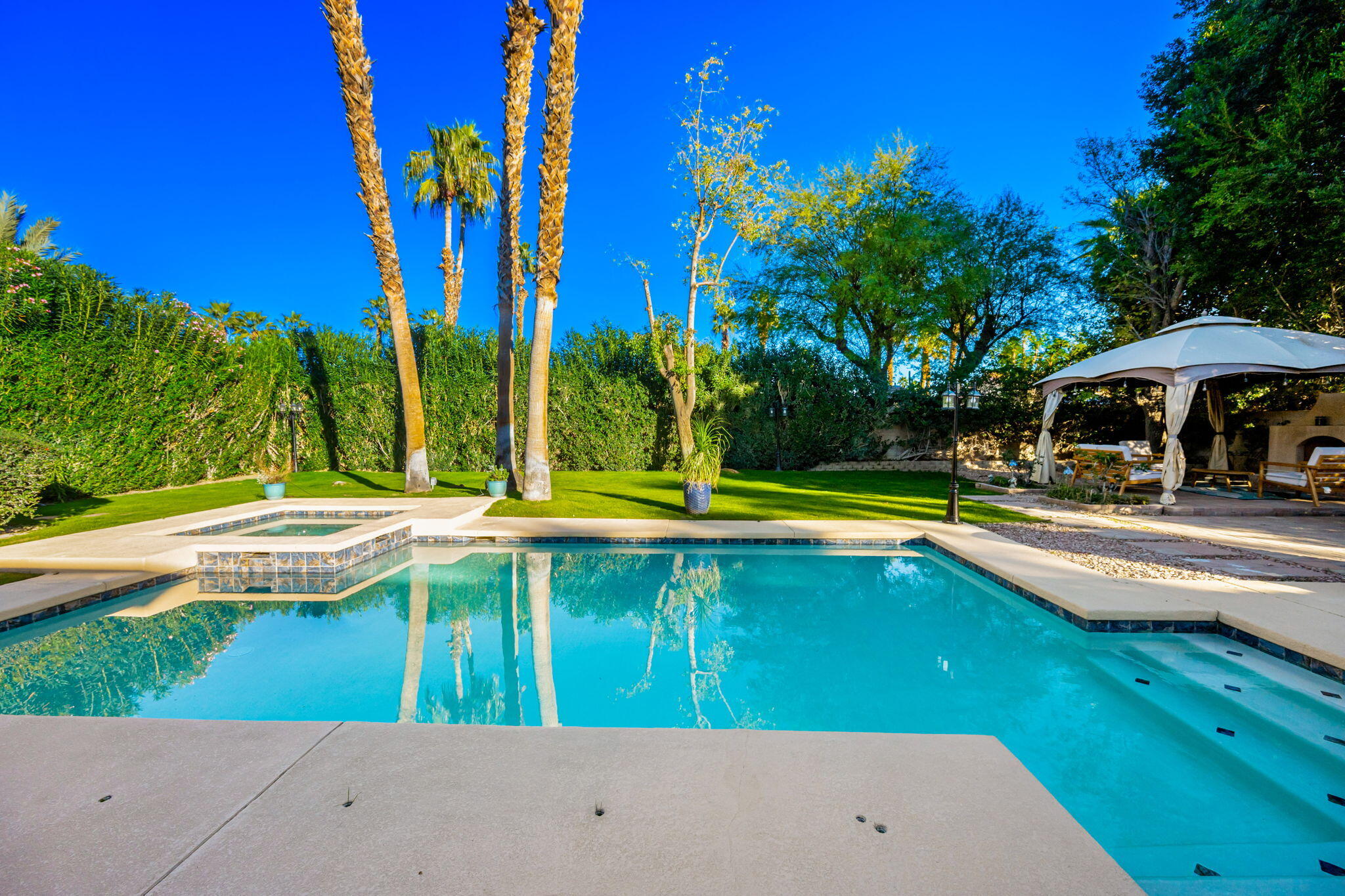 39790 Regency Way Palm Desert, CA 92211 - Photo 29 of 59 a view of a swimming pool with lawn chairs under an umbrella