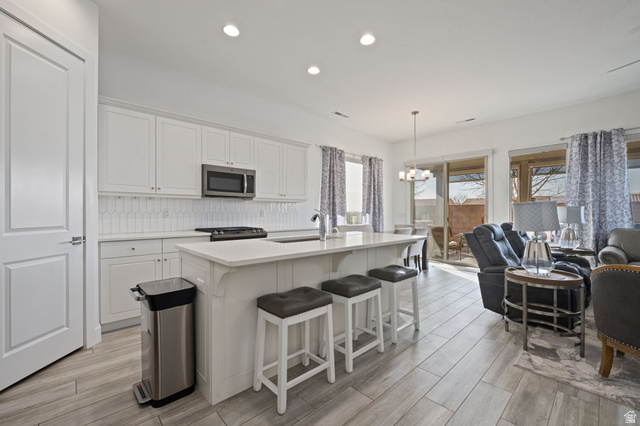 4708 Martin Drive St. George, UT 84790 - Photo 10 of 28 Kitchen with white cabinets, recessed lighting, an island with sink, appliances with stainless steel finishes, and hanging light fixtures