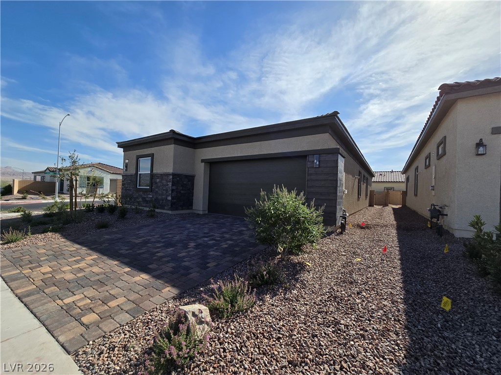 852 Weston Ridge Street Henderson, NV 89011 - Photo 2 of 28 A contemporary single-story residence boasts a paver driveway and well-maintained desert landscaping.