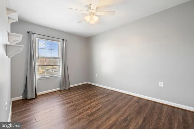 an empty room with wooden floor closet and windows
