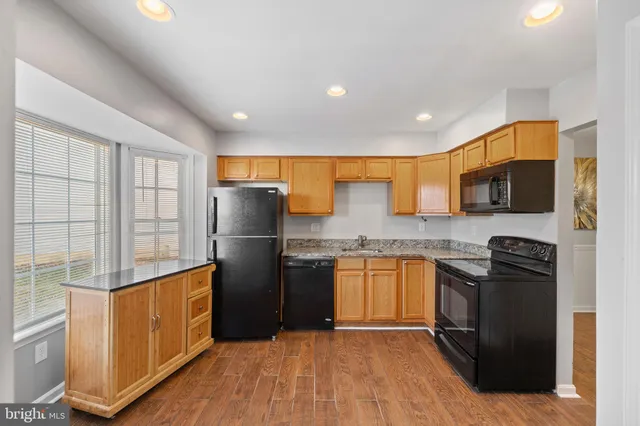 a kitchen with stainless steel appliances granite countertop refrigerator a sink a stove top oven and wooden floor