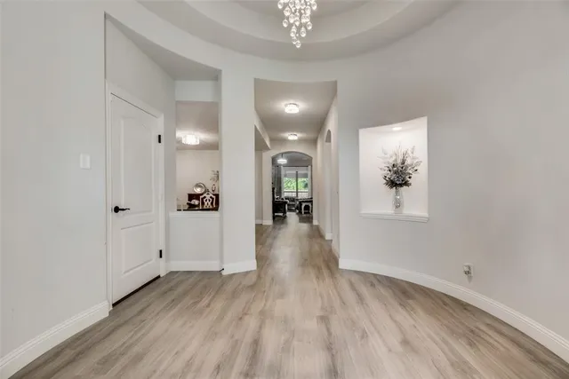 a view of a hallway with wooden floor and a chandelier