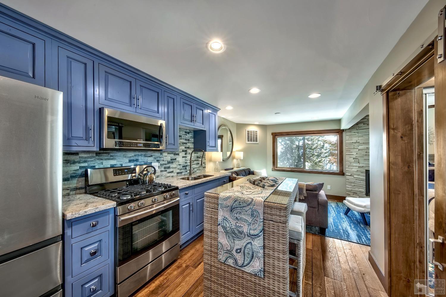 416 Maryanne Drive Stateline, NV 89449 - Photo 21 of 32 a kitchen with stainless steel appliances granite countertop a stove top oven a sink dishwasher a dining table and chairs with wooden floor