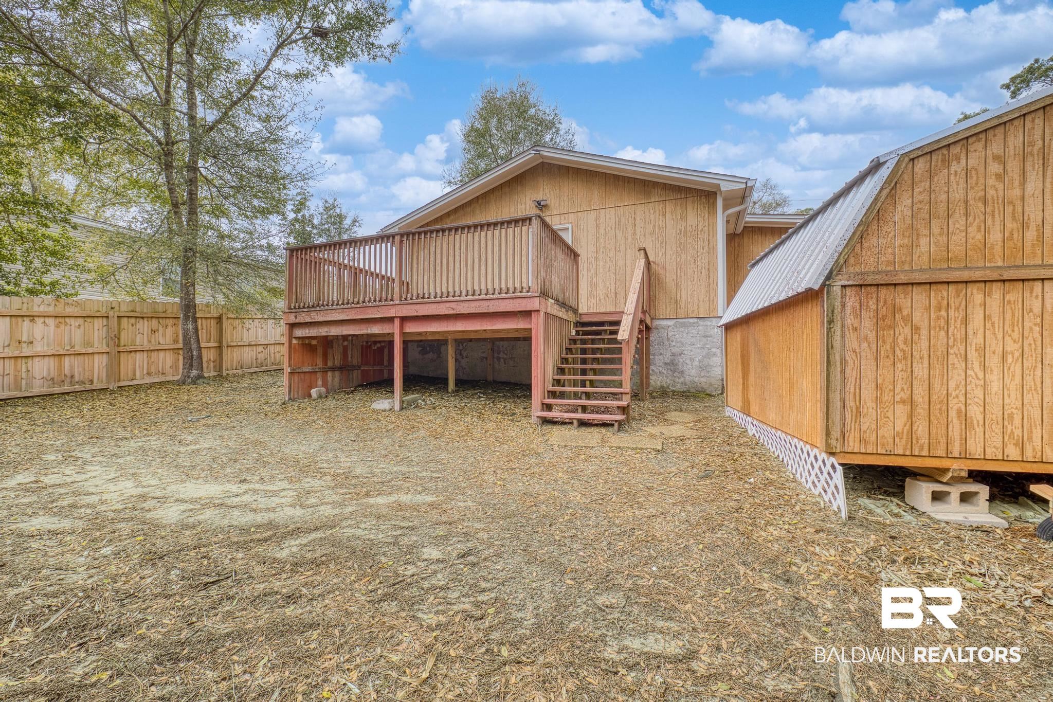 1437 Rio Circle Lillian, AL 36549 - Photo 24 of 46 Back of property with a deck, an outdoor structure, and a metal roof