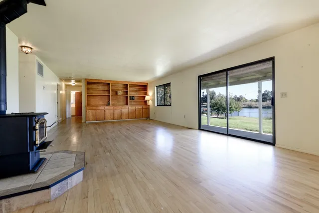 a view of empty room with wooden floor and fireplace