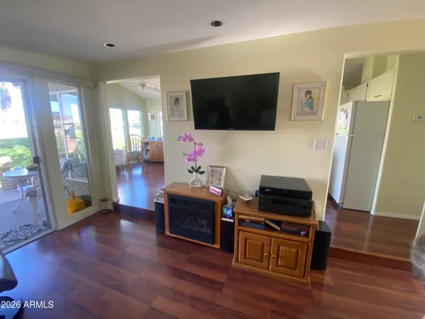 a living room with furniture a flat screen tv and a refrigerator