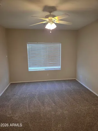 an empty room with a chandelier fan and windows