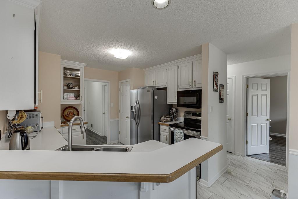1262 Bowman Road Lawrenceville, GA 30045 - Photo 12 of 32 a kitchen with stainless steel appliances kitchen island granite countertop a refrigerator and a stove top oven