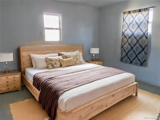 a large bed sitting in a bedroom next to a window with a wooden floor