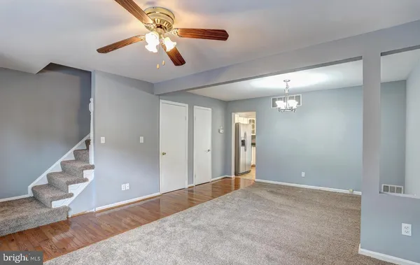 a view of a livingroom with a chandelier fan and wooden floor