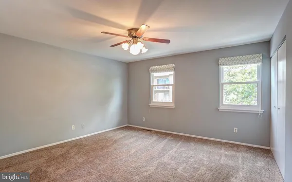 an empty room with windows and fan