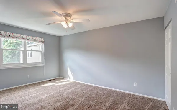 an empty room with a window and a ceiling fan