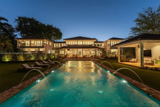 front view of a brick house with a large window plants and palm trees