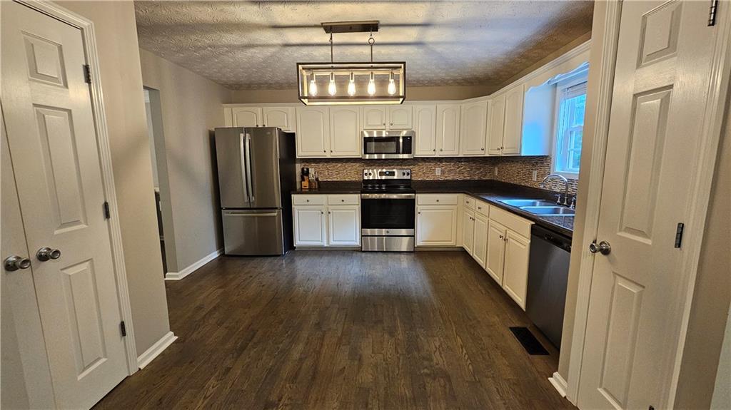 147 Oliver Drive Dallas, GA 30132 - Photo 10 of 55 a kitchen with granite countertop a refrigerator a sink dishwasher a stove and white cabinets with wooden floor