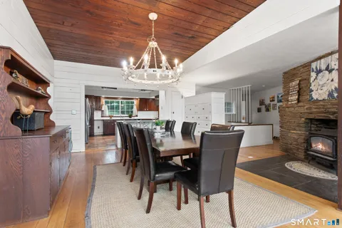 a kitchen with stainless steel appliances kitchen island granite countertop a refrigerator a stove a sink dishwasher a dining table and chairs with white cabinets