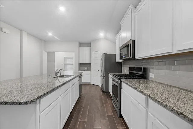 a kitchen with stainless steel appliances granite countertop a sink a stove and a refrigerator