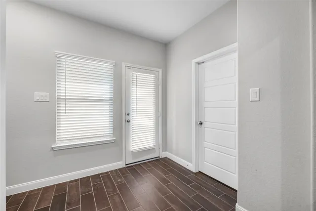 a view of an empty room with wooden floor and a window