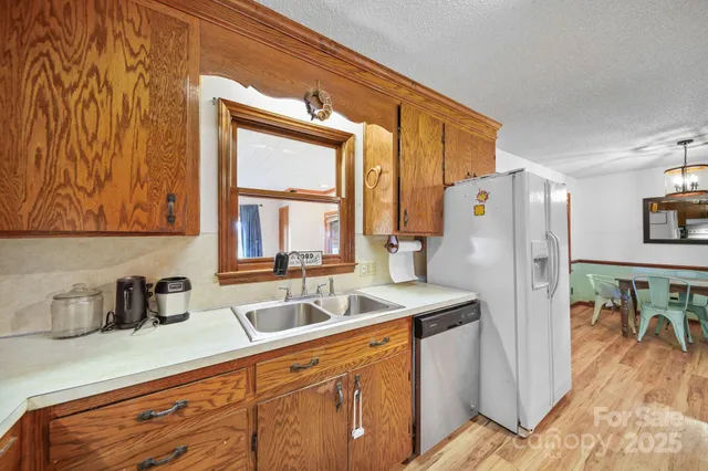 a kitchen with stainless steel appliances a refrigerator a sink a stove and white cabinets with wooden floor