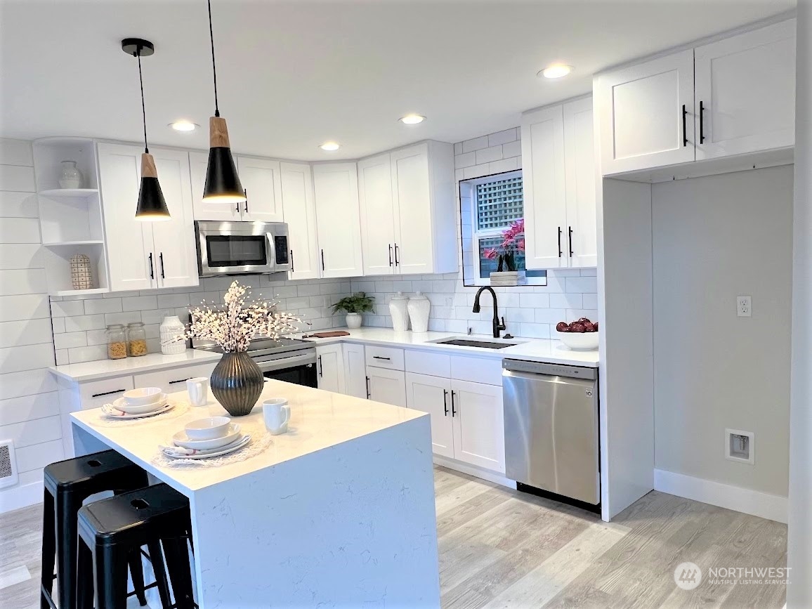 3303 31st Avenue Southwest, Unit B Seattle, WA 98126 - Photo 12 of 26 a kitchen with kitchen island granite countertop a sink cabinets and stainless steel appliances