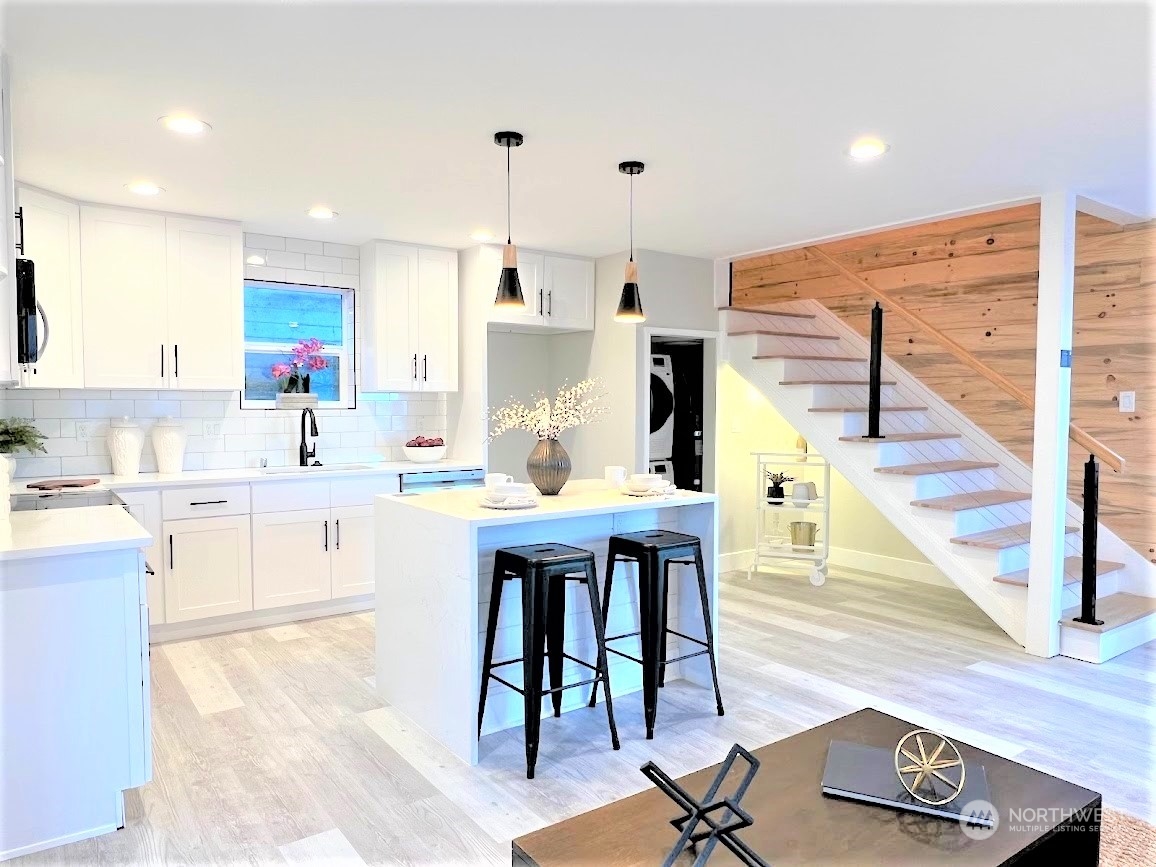3303 31st Avenue Southwest, Unit B Seattle, WA 98126 - Photo 13 of 26 a open kitchen with stainless steel appliances kitchen island granite countertop a sink dishwasher and white cabinets with wooden floor