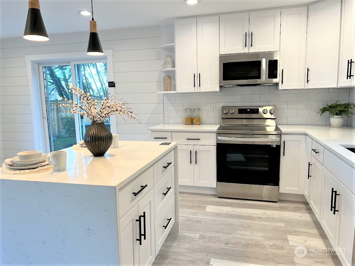 3303 31st Avenue Southwest, Unit B Seattle, WA 98126 - Photo 6 of 26 a kitchen with stainless steel appliances a stove sink microwave and cabinets