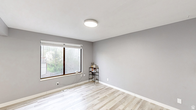 630 1100 West Provo, UT 84601 - Photo 12 of 64 Bright interior space featuring a large window with white blinds, light wood-finish flooring, a contemporary ceiling light fixture, and neutral gray walls with white baseboards
