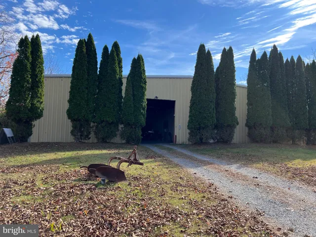 a view of a barn with yard and large trees