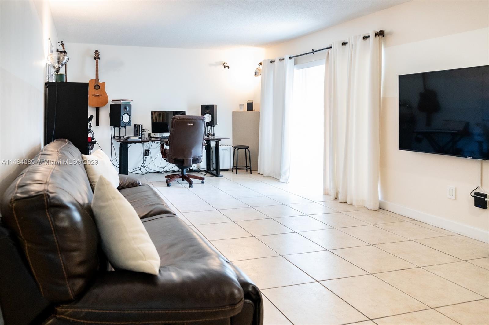 7715 Southwest 86th Street, Unit A2307 Miami, FL 33143 - Photo 11 of 89 a living room with furniture and a flat screen tv