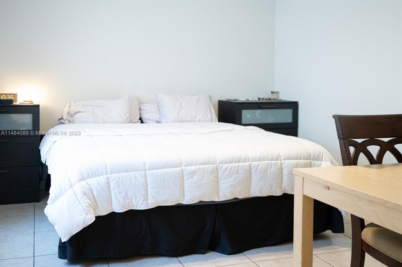 7715 Southwest 86th Street, Unit A2307 Miami, FL 33143 - Photo 47 of 89 a bedroom with a bed and a lamp on table