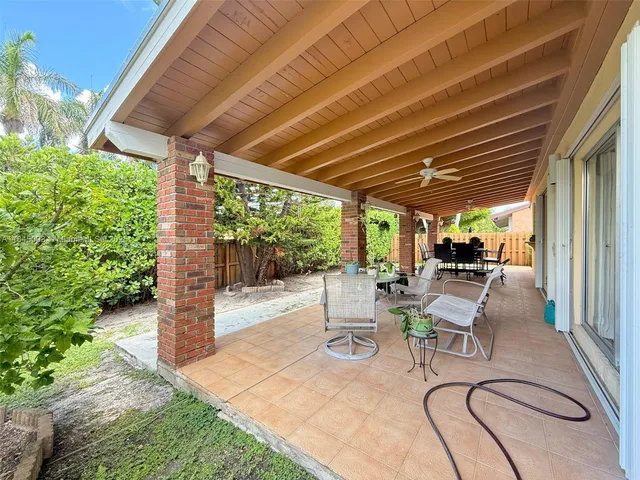 a view of a patio with table and chairs potted plants with wooden floor and fence