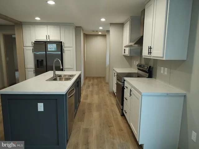 a kitchen with a sink a counter top space stainless steel appliances and cabinets